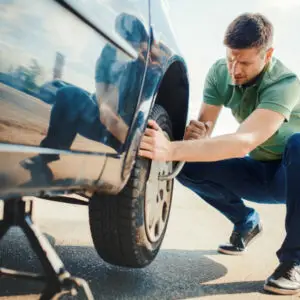 Équipier d'EpavistePro changeant efficacement une roue pour un client, illustrant le professionnalisme et la rapidité du service de dépannage de l'entreprise.